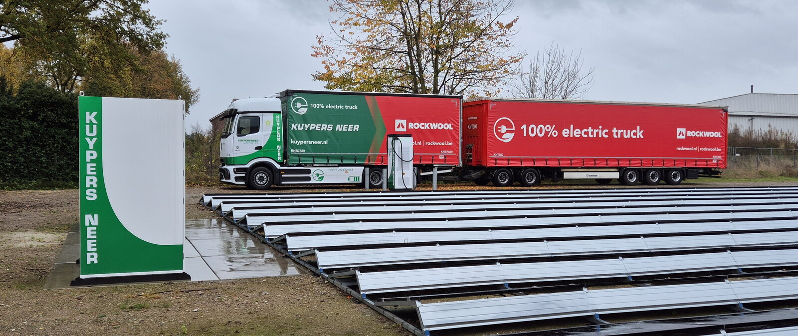 Elektrische truck Rockwool staat aan oplader met zonnepanelen ernaast