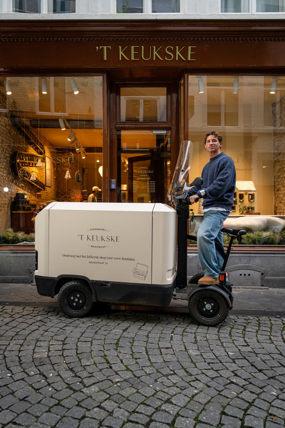 Dave van 't Keukske op zijn licht elektrische voertuig bij zijn winkel